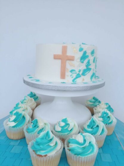 Buttercream vanilla cake decorated in blue and white theme with gold cross. 24 matching cupcakes from Blessing's bakery, Halden